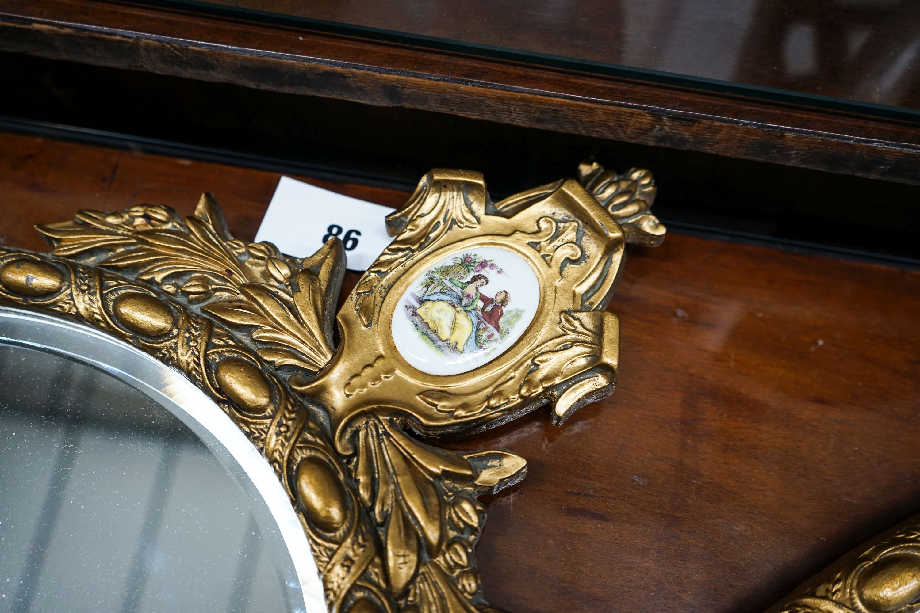 A pair of oval gilt framed wall mirrors inset porcelain plaques, width 42cm, height 78cm